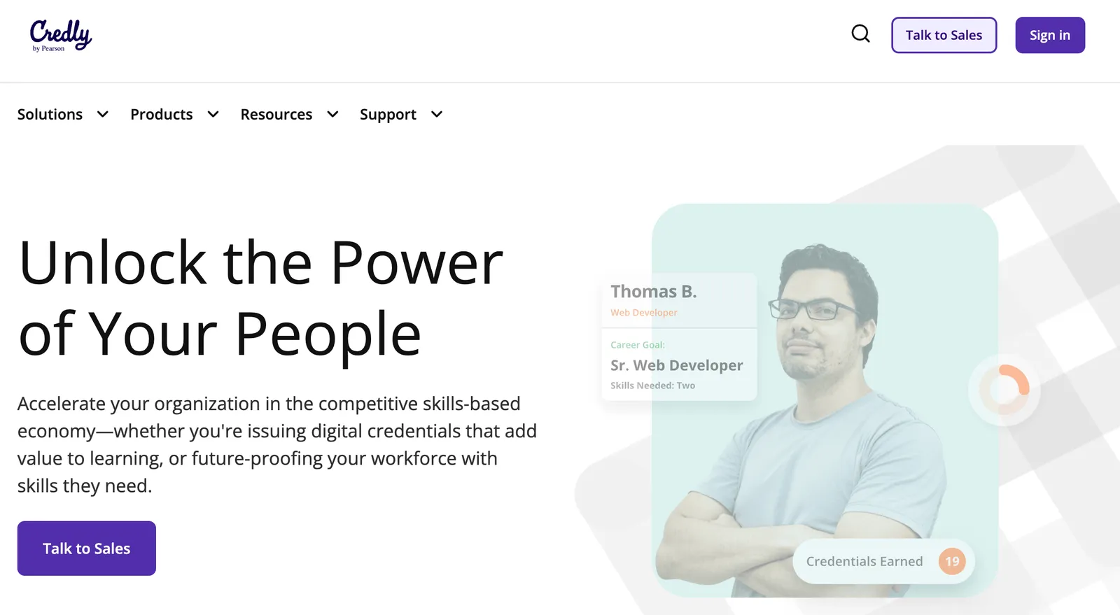The Credly by Pearson homepage headline reading Unlock the Power of Your People, with a Talk to Sales call to action and a credential holder profile